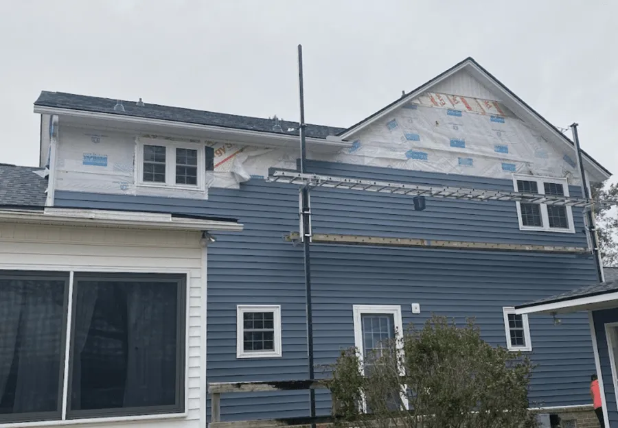 Home with new blue vinyl siding going up